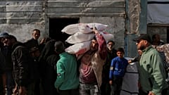 فلسطينيون يتسلمون أكياساً من الدقيق ومساعدات إنسانية أخرى وزعتها وكالة (الأونروا) في جباليا بقطاع غزة، يوم الثلاثاء 25 مارس/آذار 2025.