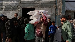 فلسطينيون يتسلمون أكياساً من الدقيق ومساعدات إنسانية أخرى وزعتها وكالة (الأونروا) في جباليا بقطاع غزة، يوم الثلاثاء 25 مارس/آذار 2025.