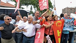 Διαδηλωτές από το Λαϊκό Απελευθερωτικό Κόμμα ανεμίζουν σημαίες και κρατούν πλακάτ που γράφει «Φονικό ΝΑΤΟ, φύγετε από τη χώρα μας»,