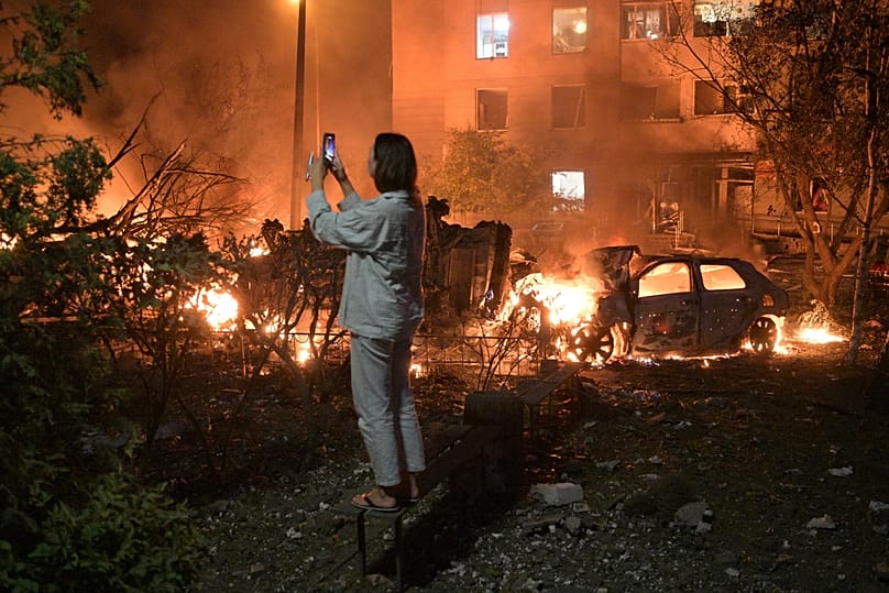 A woman takes photo of destructions following Russian missile attacks in Kyiv, Ukraine, Monday, July 6, 2026. 