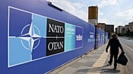 A man walks past a banner ahead of the NATO Summit in Ankara, Turkey.