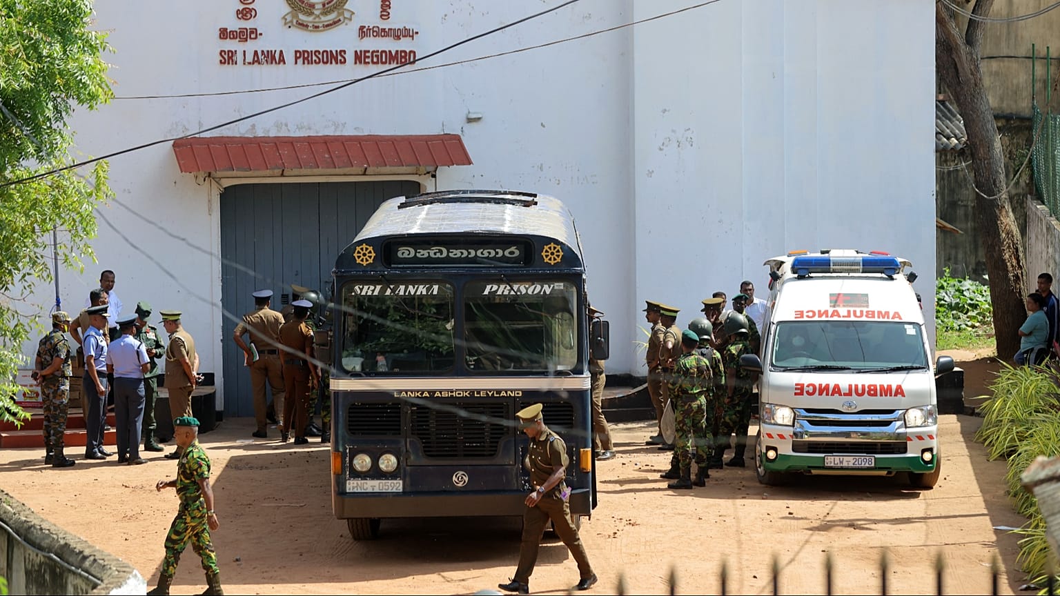 Security personnel stand guard in the compound of a prison where deadly clashes broke out in Negombo, 6 July, 2026