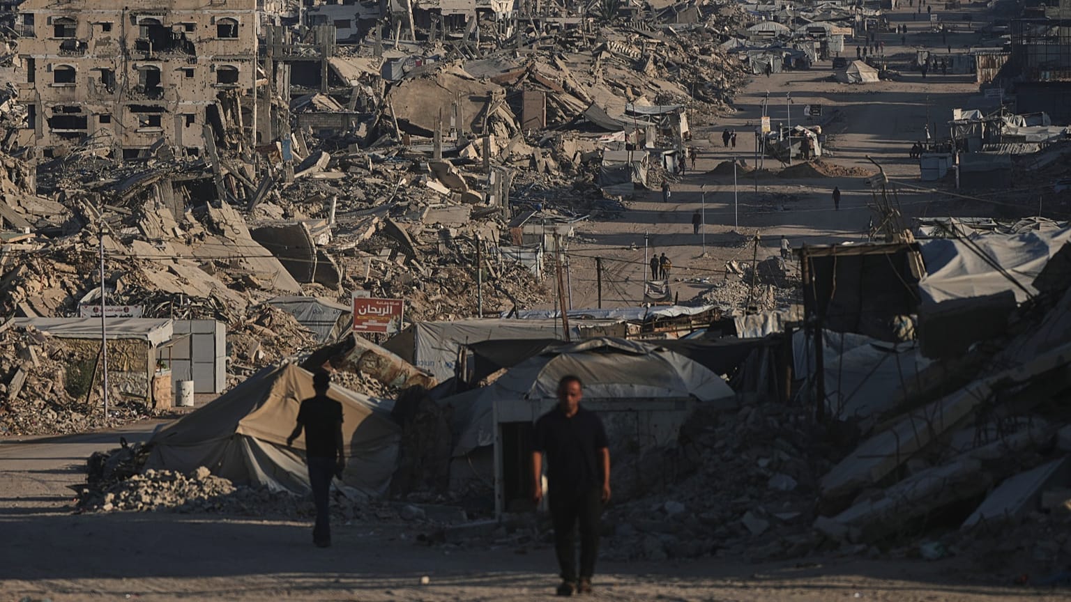 Palestinians walk along a road surrounded by buildings destroyed in Israeli military strikes in Jabaliya, 2 July, 2026