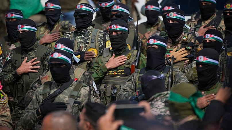 Hamas fighters stand in formation ahead of a ceremony to hand over Israeli hostages to the Red Cross in Nuseirat, 22 February, 2025