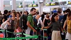Pasajeros esperan para pasar el control de seguridad en el aeropuerto de Barcelona, donde afrontan largas colas de seguridad.