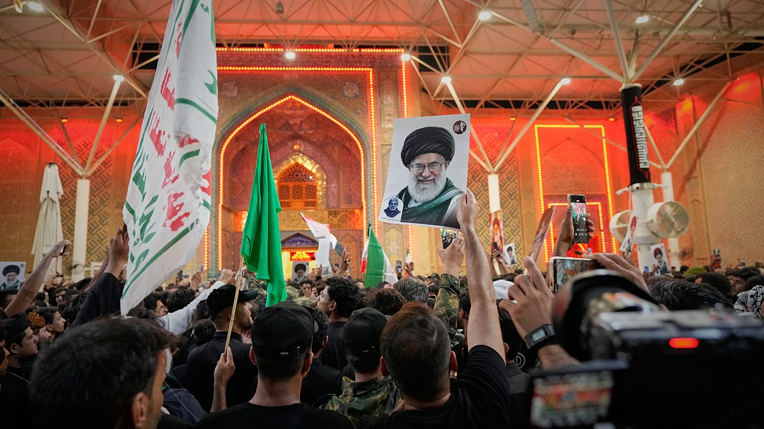 يلوح المشيعون بالأعلام الدينية الشيعية وصورة المرشد الأعلى الإيراني الراحل آية الله علي خامنئي خارج مرقد الإمام علي عشية مراسم الجنازة في النجف، العراق، الثلاثاء 7 يوليو 2026.