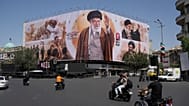 Motorcycles drive past a billboard showing the late Iranian Supreme Leader Ayatollah Ali Khamenei in Islamic Revolution Square in Tehran, Iran, Sunday, July 5, 2026. 