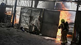 رجل يطفئ النيران في ورشة متضررة عقب إطلاق صواريخ في مدينة بيتاح تكفا بإسرائيل، الثلاثاء 31 مارس/آذار 2026