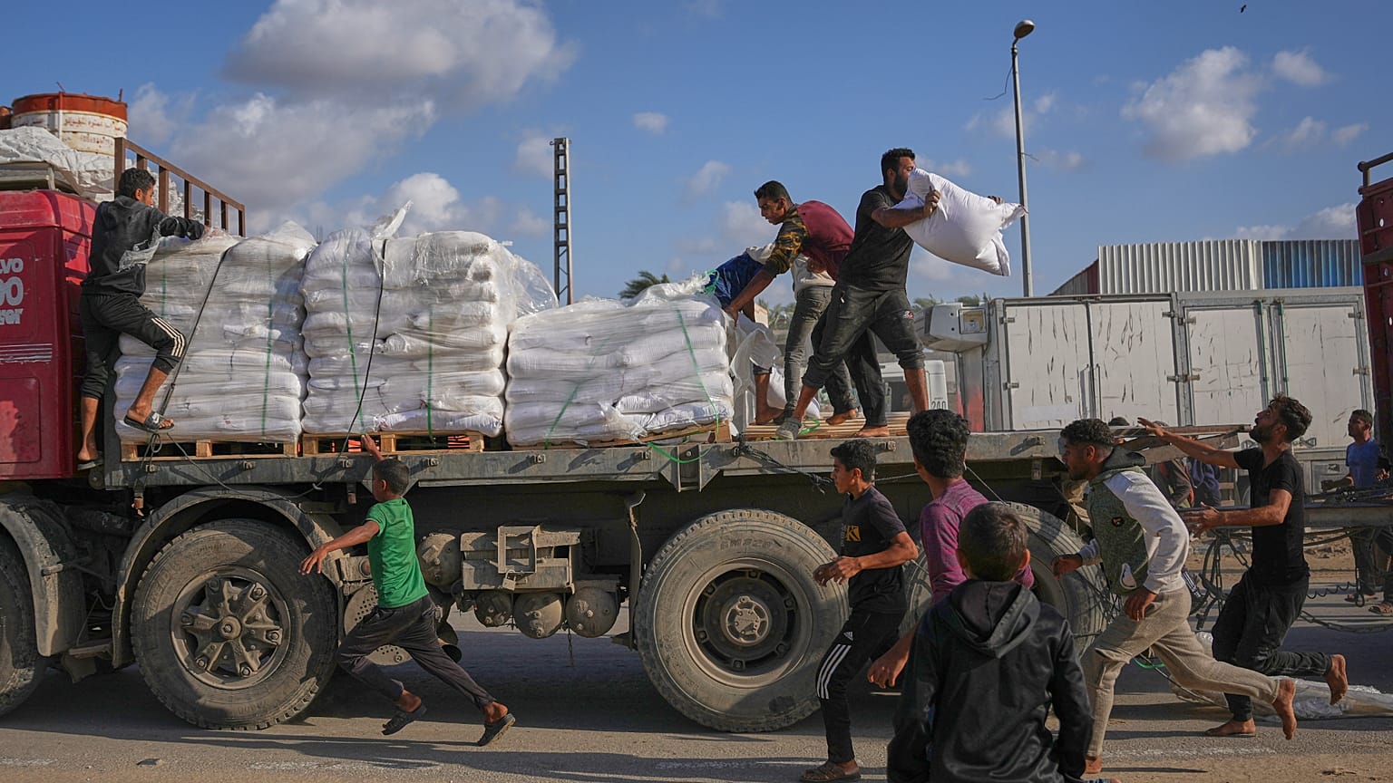 فلسطينيون يحصلون على أكياس طحين من شاحنة مساعدات تابعة لبرنامج الأغذية العالمي أثناء مرورها في دير البلح وسط قطاع غزة، في 15 نوفمبر 2025.