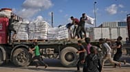 فلسطينيون يحصلون على أكياس طحين من شاحنة مساعدات تابعة لبرنامج الأغذية العالمي أثناء مرورها في دير البلح وسط قطاع غزة، في 15 نوفمبر 2025.