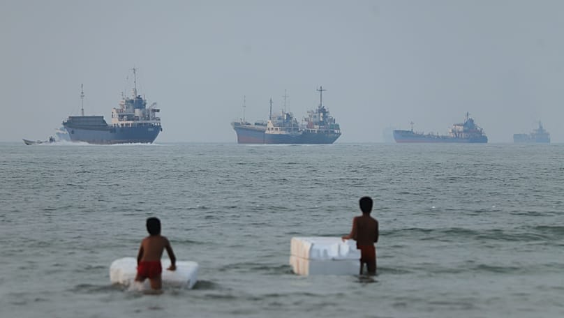 Dos niños en aguas poco profundas con flotadores mientras se observan buques de carga en el estrecho de Ormuz, frente a Bandar Abbas, Irán, el 30 de junio de 2026.