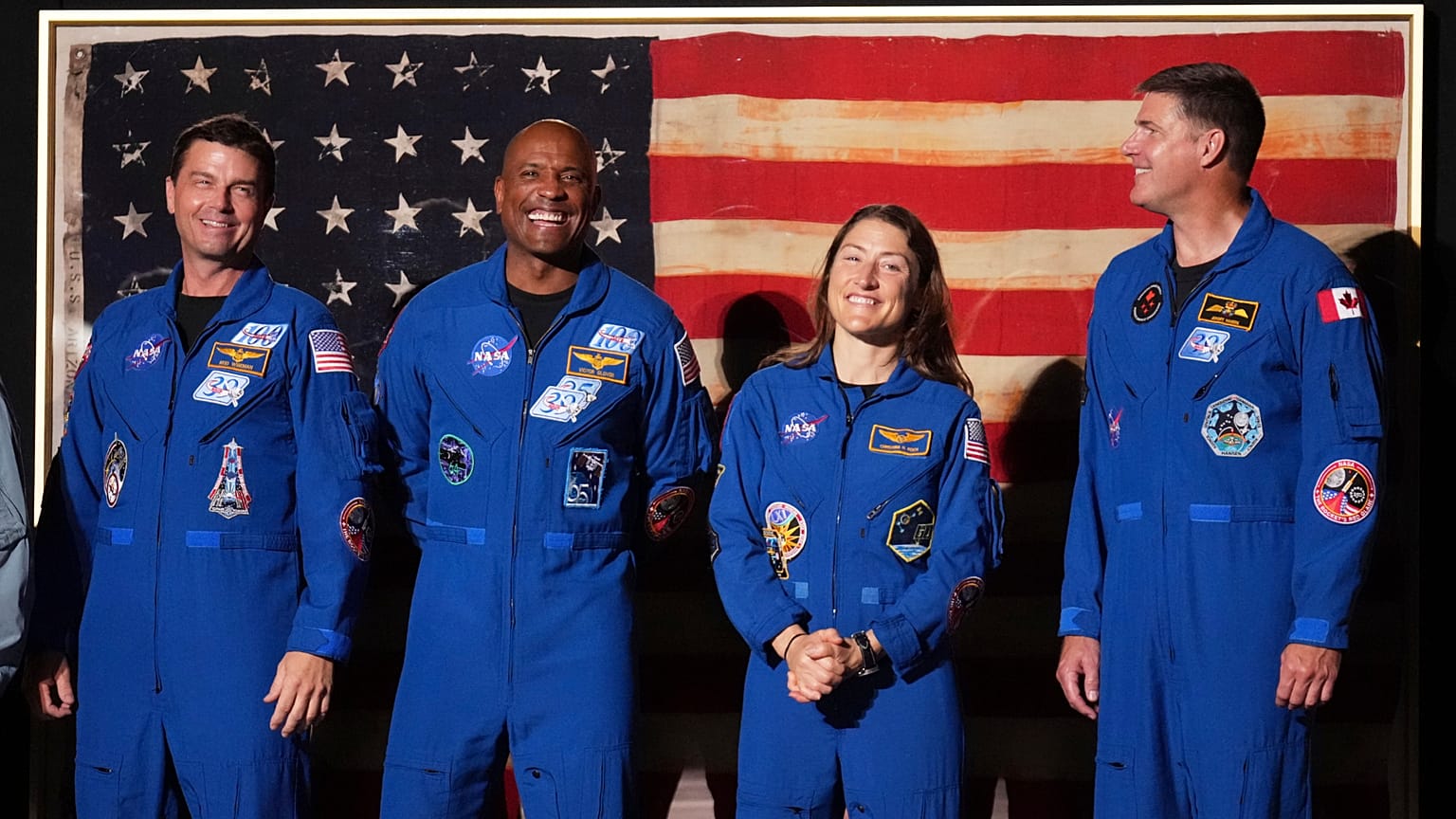 Les astronautes d'Artemis II Reid Wiseman (à gauche), Victor Glover, Christina Koch et Jeremy Hansen debout tandis que Donald Trump parle lors de Salute to America.