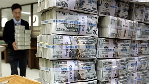 A South Korean bank clerk carries bundles of U.S. banknotes at a local bank in Seoul, Wednesday, Jan. 4, 2006. 