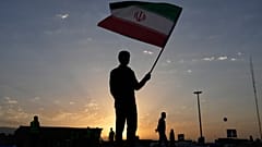 رجل يحمل العلم الإيراني مع شروق الشمس قبل جنازة المرشد الأعلى علي خامنئي في طهران، السبت 4 يوليو 2026