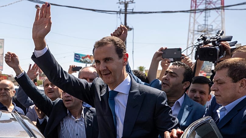 O antigo presidente sírio Bashar al-Assad acena a apoiantes numa assembleia de voto na cidade de Douma, em 26 de maio de 2021