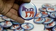 Egy férfi egy demokrata párti kitűzőt tart a kezében egy amerikai elnökválasztási rendezvényen.