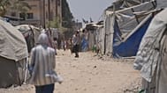 نازحون فلسطينيون يسيرون بين الخيام في دير البلح بوسط قطاع غزة، السبت 4 يوليو 2026. (AP Photo/عبد الكريم حنا)