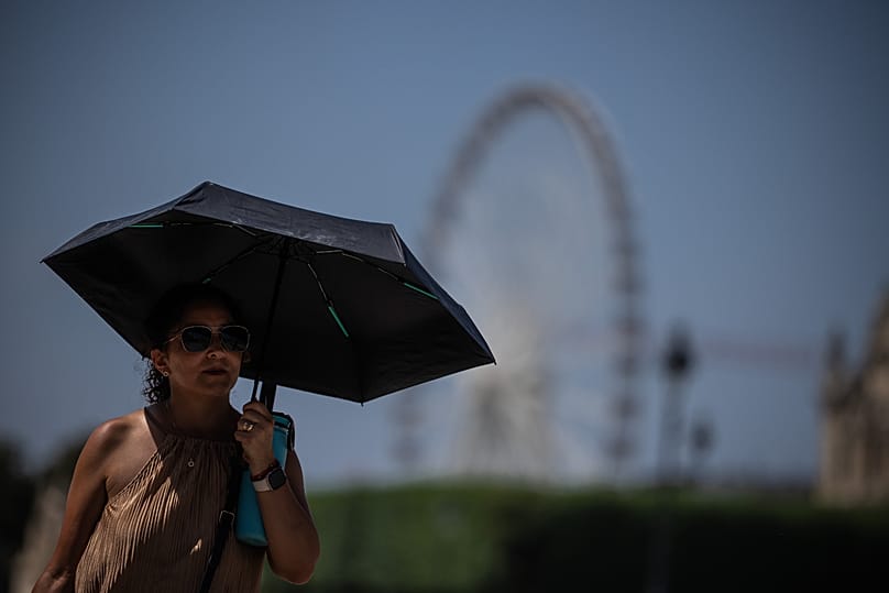 A tourist with an umbrella walks in Paris during a heat wave, 27 June, 2026