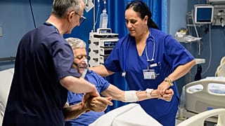 Cuban doctor Daysi Luperon Loforte helps lift up a patient hospitalized in Polistena.
