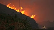 Un motorista cruza la carretera que baja de la cima, ya cubierta por el humo del incendio forestal en el Monte do Faro, en Valença do Minho (Portugal) 