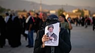امرأة تغطي وجهها بصورة المرشد الأعلى الإيراني المقتول آية الله علي خامنئي بينما يتجمع المشيعون خلال مراسم الجنازة في مسجد الإمام الخميني الكبير في طهران، إيران، الأحد 5 يوليو 