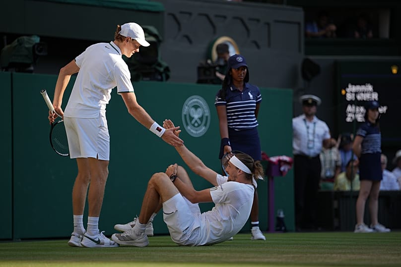 Jannik Sinner of Italy, left helps up Alexander Zverev of Germany who fell during the men's singles final at Wimbledon Tennis Championships in London, Sunday, July 12, 2026.