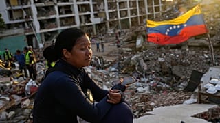 A woman sits amid the rubble of a building waiting to find her two children after the earthquakes in La Guaira, 12 July, 2026