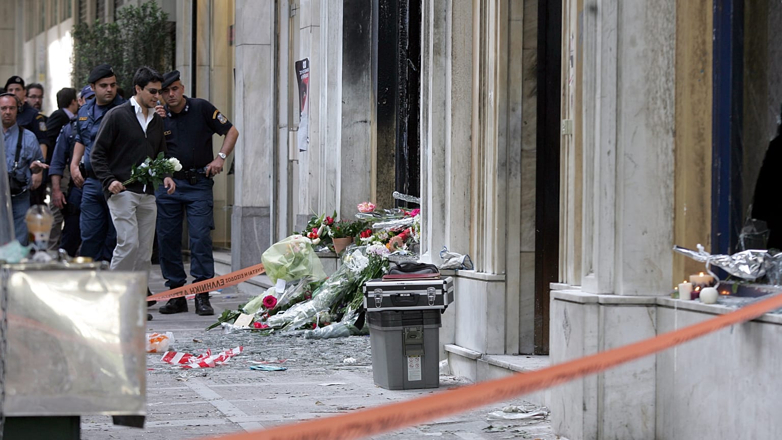 Un hombre deja flores en la sucursal de Marfin en la calle Stadiou después del ataque mortal ocurrido durante una manifestación en 2010