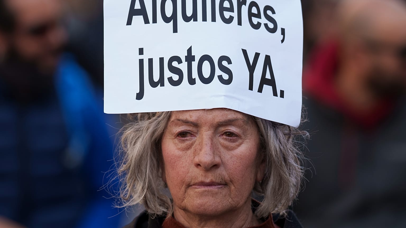 Uma mulher traz na cabeça um cartaz em espanhol: "Rendas justas já", durante uma manifestação em 2025 contra a subida dos preços das rendas
