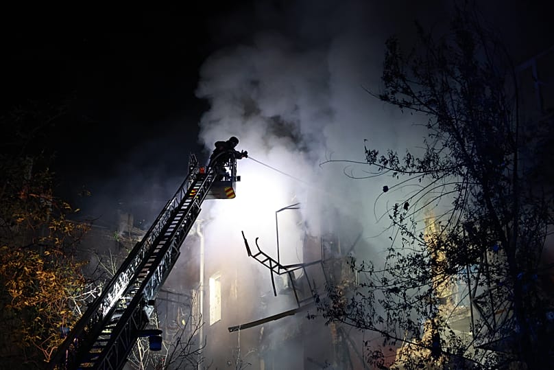 Rescue workers try to put out a fire of a residential building burning after a Russian drone attack on Zaporizhzhia, 12 July, 2026
