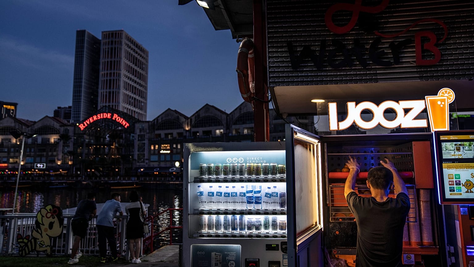A worker restocks a freshly squeezed orange juice vending machine in Singapore, 13 July, 2023
