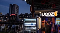A worker restocks a freshly squeezed orange juice vending machine in Singapore, 13 July, 2023