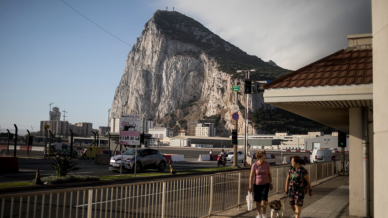 ARCHIVO - Con el Peñón de Gibraltar de fondo, varias personas cruzan la pista del aeropuerto de Gibraltar el jueves 24 de junio de 2021.