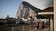 ARCHIVO - Con el Peñón de Gibraltar de fondo, varias personas cruzan la pista del aeropuerto de Gibraltar el jueves 24 de junio de 2021.