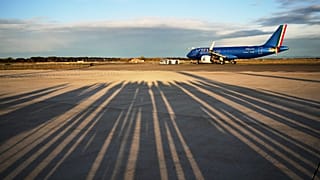 Reporters' shadows are cast on the tarmac as they wait for the plane to depart that is transporting Pope Leo XIV Fiumicino airport in Rome, Thursday, Nov. 27, 2025