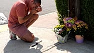 Un hombre se lamenta y reza frente a un altar improvisado donde falleció el hombre.
