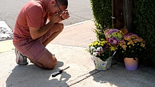 Un hombre se lamenta y reza frente a un altar improvisado donde falleció el hombre.