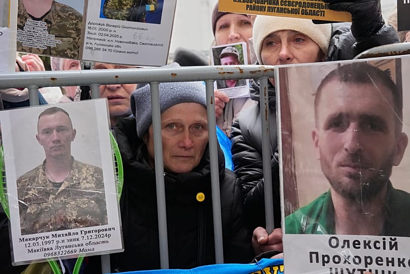 Des personnes brandissent des photos de leurs proches tandis que des soldats ukrainiens rentrent de captivité lors d'un échange de prisonniers de guerre, le 11 avril 2026
