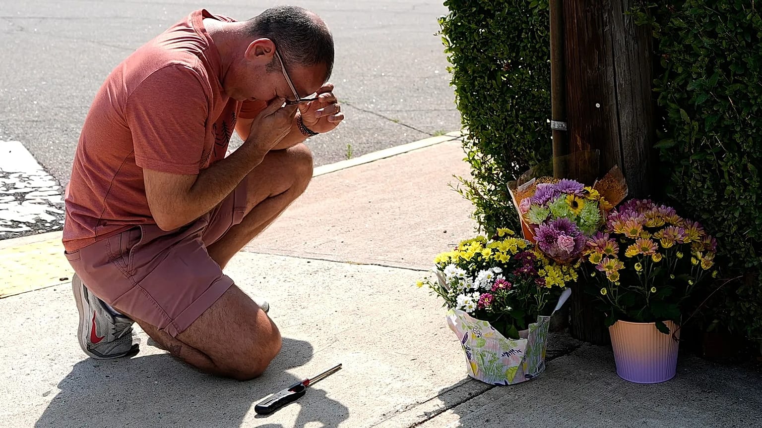 A man grieves and prays at a memorial at the spot where the victim died.