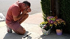 A man grieves and prays at a memorial at the spot where the victim died.