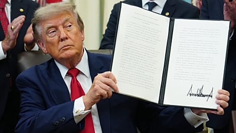 US President Donald Trump holds a signed executive order in the Oval Office of the White House, 13 July, 2026
