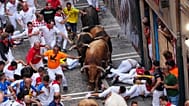 Revellers run alongside La Palmosilla's fighting bull during the sixth running of the bulls at the San Fermín festival, 12 July, 2026