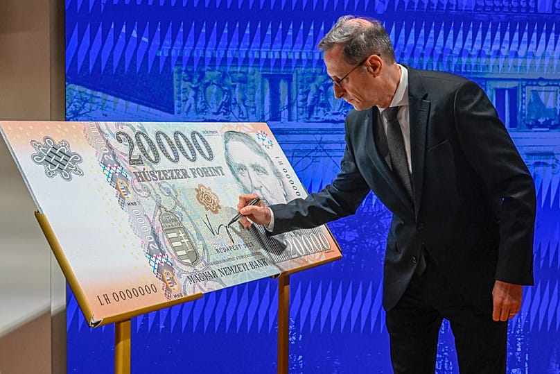 Varga Mihály, a Magyar Nemzeti Bank (MNB) elnöke szimbolikusan aláírja egy 20 000 forintos bankjegy nagy méretű másolatát