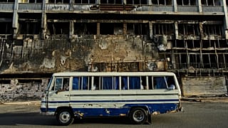 Un autobus passa davanti a un hotel distrutto durante la guerra nel centro di Khartoum, 19 aprile 2026
