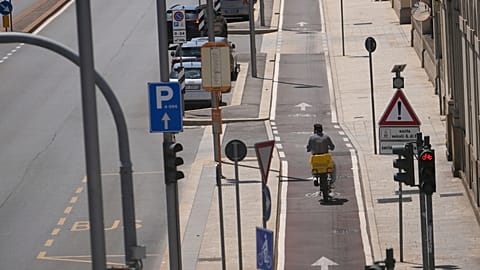 Ένας διανομέας φαγητού κινείται σε άδειο, ηλιόλουστο δρόμο στο Μιλάνο, Ιταλία, την Τετάρτη 8 Ιουλίου 2026. (AP Photo/Luca Bruno)