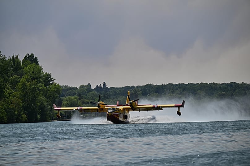 Un avion bombardier d'eau Canadair prélève de l'eau dans la Seine pour lutter contre les incendies de forêt dans la région de Fontainebleau, en France, lundi 13 juillet 2026. 
