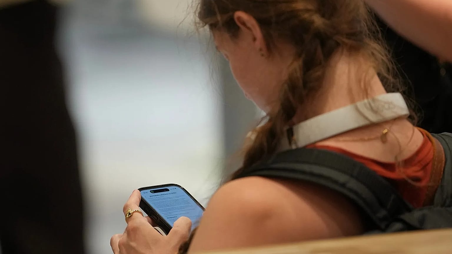 A teenager looks at her mobile phone in London, Monday, June 15, 2026. (AP Photo/Kin Cheung)