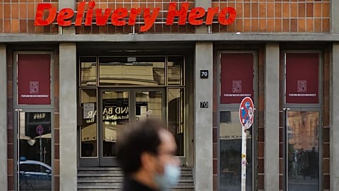 File - A man with a face mask stand in front of the entrance of the headquarters of the food delivery company 'Deleivery Hero' in Berlin, Germany, Wednesday, 28 Oct. 2020. 