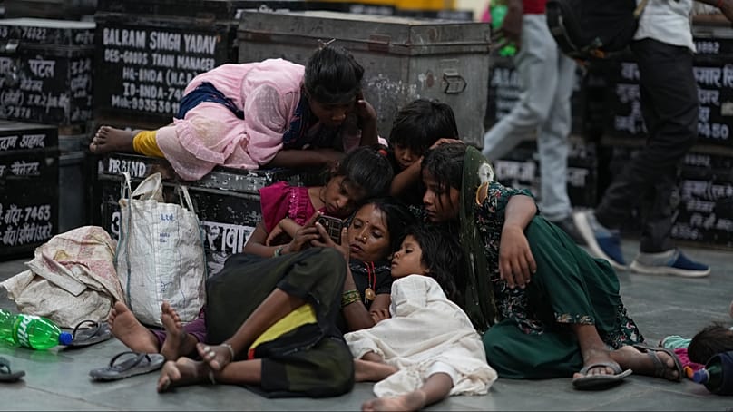 Des enfants se rassemblent autour d’un téléphone portable tandis que des habitants se reposent dans une gare pour échapper à la chaleur à Banda, dans l’État d’Uttar Pradesh, dans le nord de l’Inde, samedi 20 juin 2026.