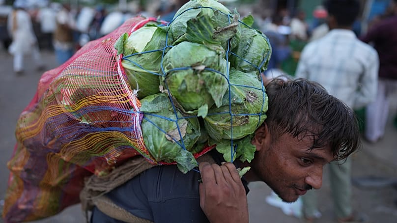 Un travailleur transporte des légumes sur un marché tôt le matin pendant une vague de chaleur à Banda.